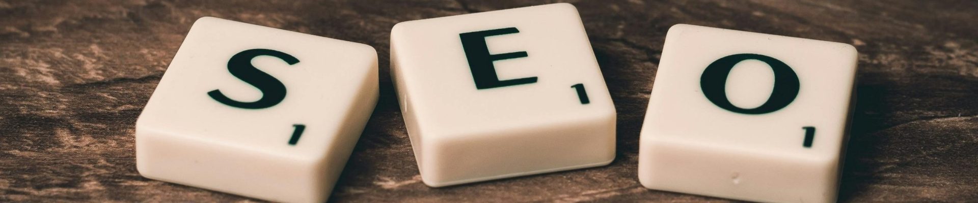 Scrabble tiles spelling 'SEO' on a wooden surface. Ideal for digital marketing themes.
